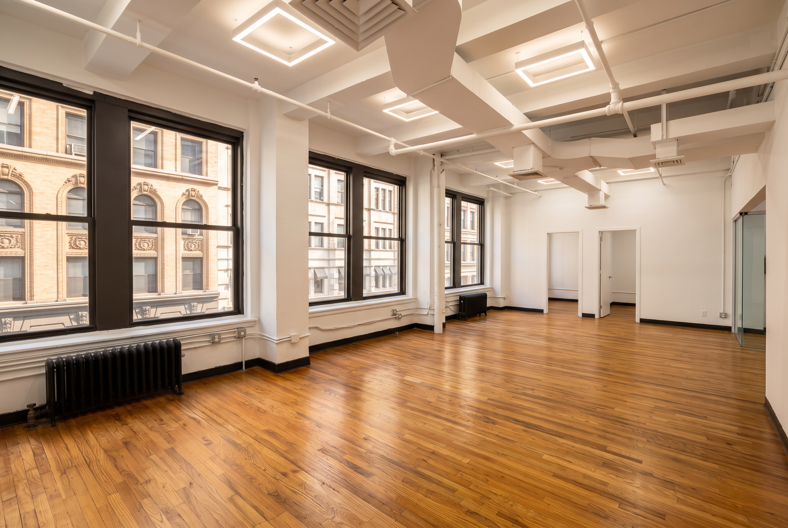 Empty full-floor prewar office with oversized windows and hardwood floors